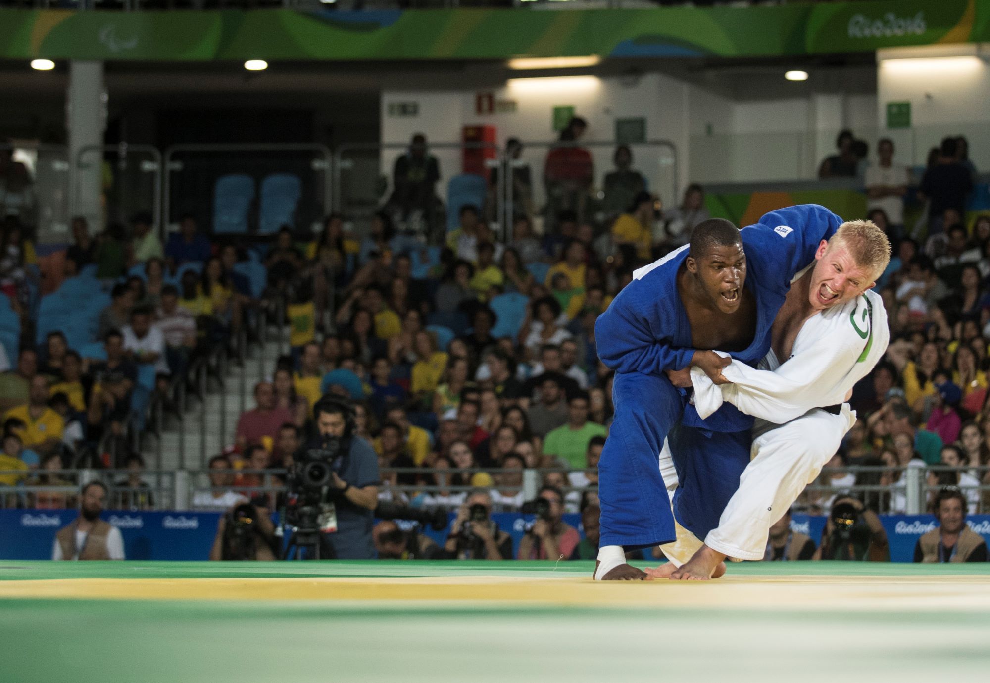 Un judokat avec un kimono bleu empoigne un judoka en kimono blanc lors des Jeux Paralympiques de Rio 2016