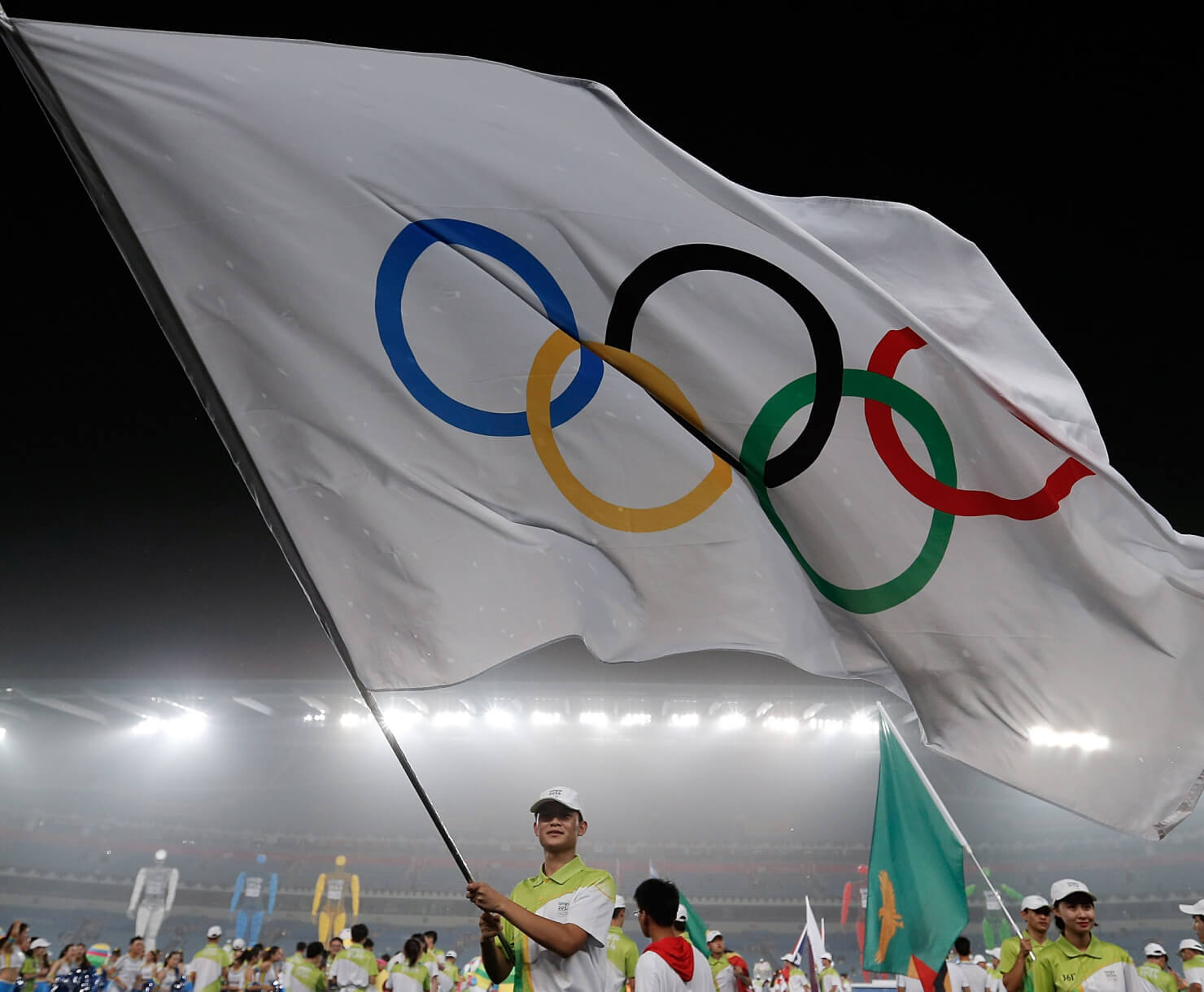 Volontaire des jeux qui porte le drapeau olympique